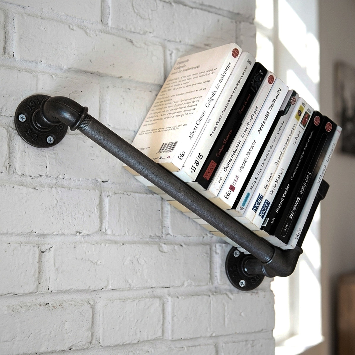 Cast iron wall bookshelf on a brick wall with books, loft setting