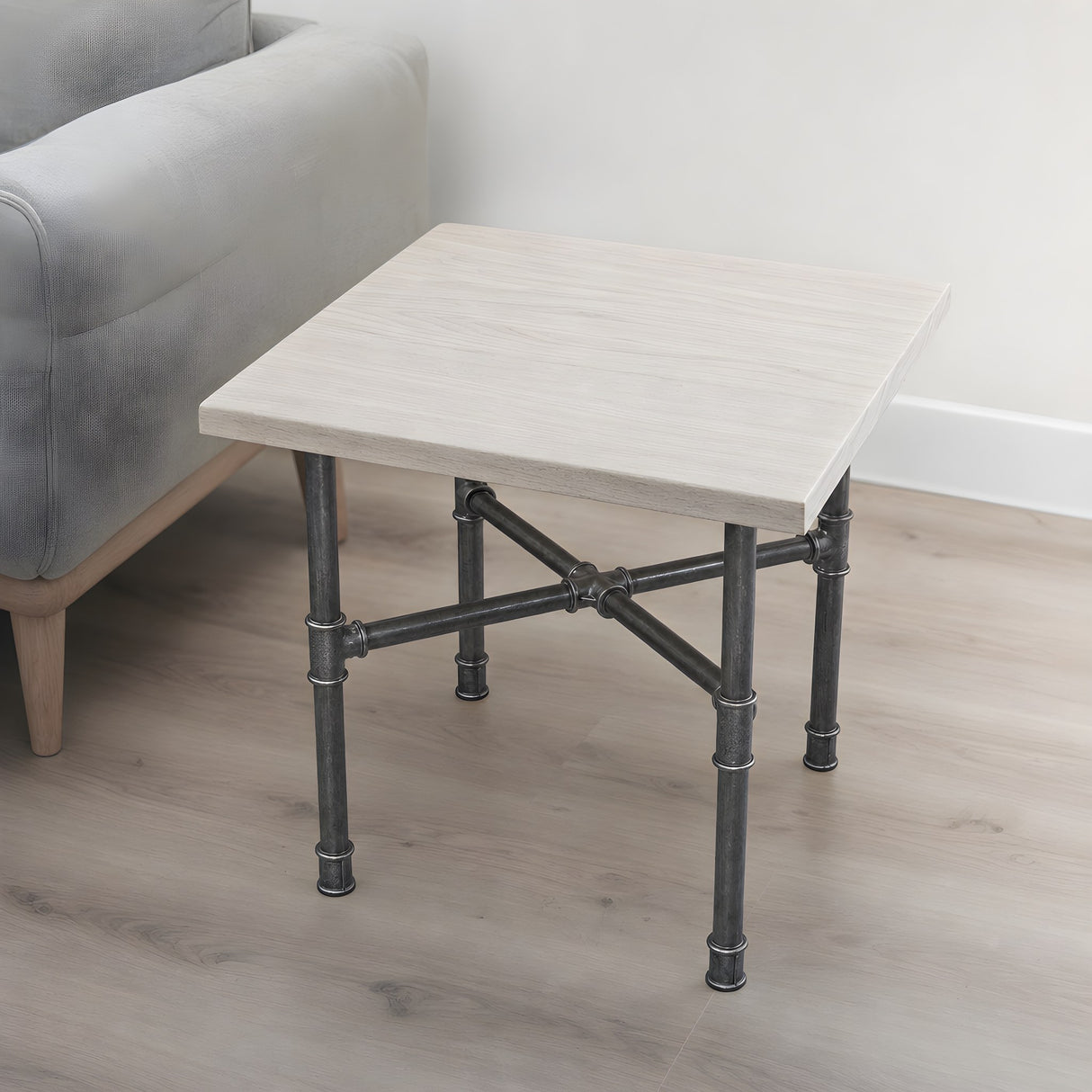 Cross-leg coffee table base, cast iron and varnished steel Ø 27 mm, shown in a room under a whitewashed ash tabletop