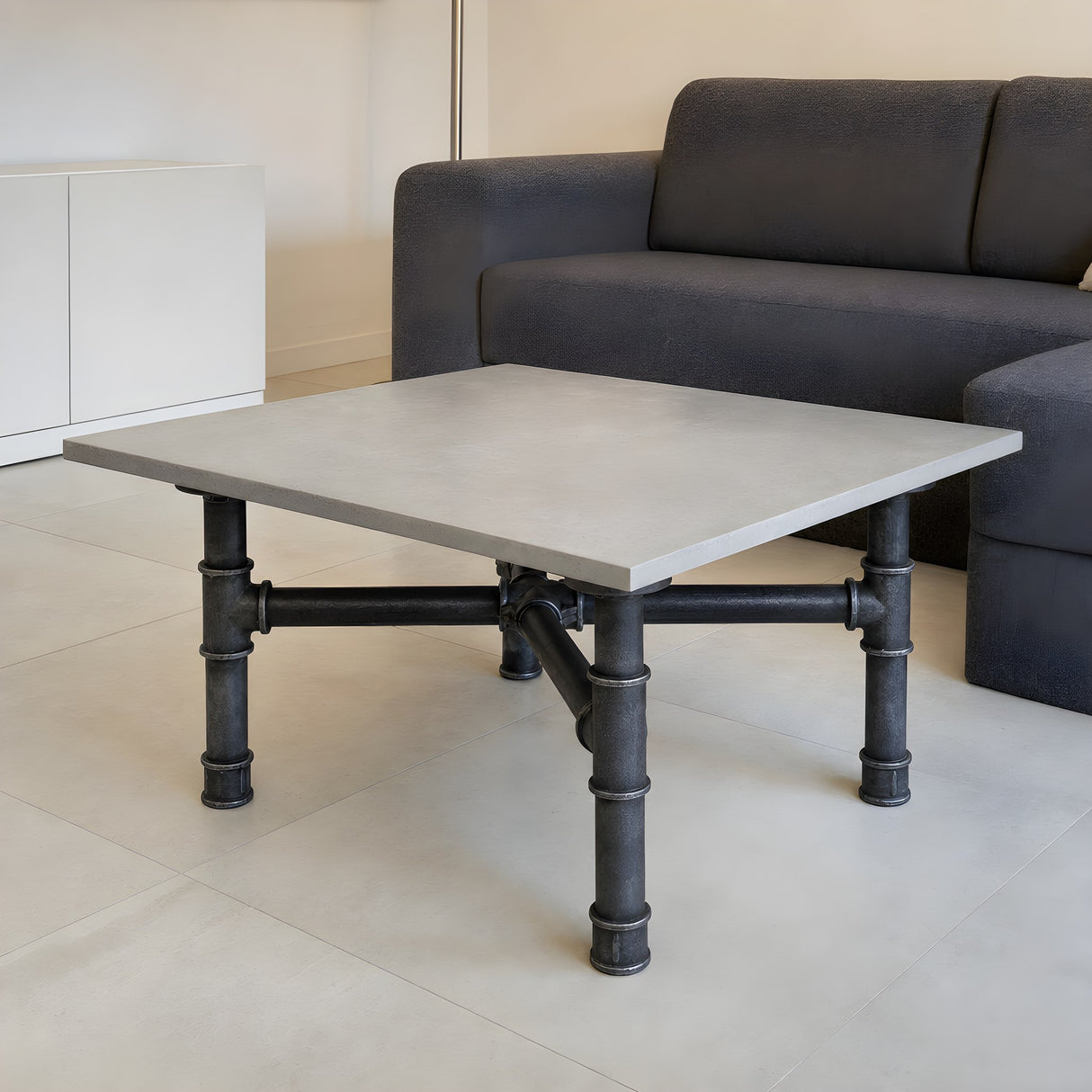 Cross-leg coffee table base, cast iron and varnished steel Ø 42 mm, shown in a room under a pale polished concrete tabletop
