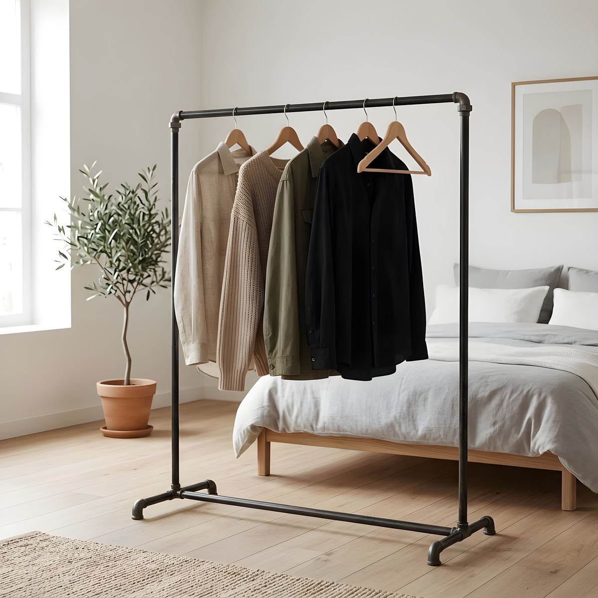 Industrial clothes rack made of black plumbing pipes in a bright bedroom, clothes on wooden hangers