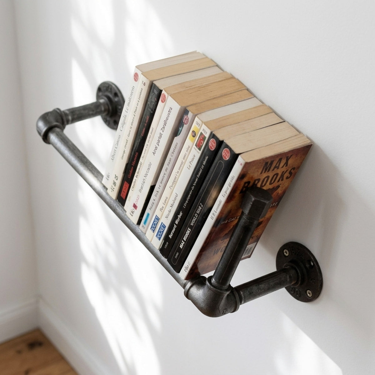 Cast iron wall bookshelf mounted on a light wall with paperbacks, room setting