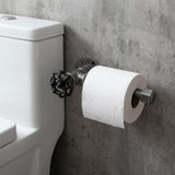 Wall-mounted black cast iron toilet paper holder with handwheel, installed next to the toilet