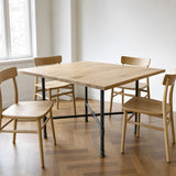 Cross-leg dining table base, cast iron and varnished steel Ø 27 mm, shown in a room under a light solid oak tabletop