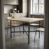 Cross-leg dining table base, cast iron and varnished steel Ø 27 mm, shown in a room under a bleached oak tabletop