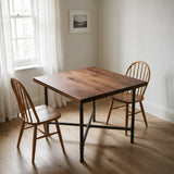 Cross-leg dining table base, cast iron and varnished steel Ø 34 mm, shown in a room under a solid walnut tabletop