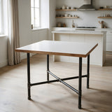 Cross-leg dining table base, cast iron and varnished steel Ø 34 mm, shown in a room under a matt white tabletop with a wood edge