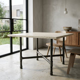 Cross-leg dining table base, cast iron and varnished steel Ø 42 mm, shown in a room under a pale terrazzo tabletop