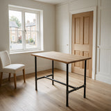 H-frame dining table base, cast iron and varnished steel Ø 27 mm, shown in a room under a light solid oak tabletop