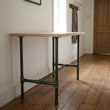 H-frame dining table base, cast iron and varnished steel Ø 27 mm, shown in a room under a birch plywood tabletop