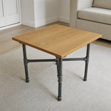 Cross-leg coffee table base, cast iron and varnished steel Ø 27 mm, shown in a room under a light oiled oak tabletop