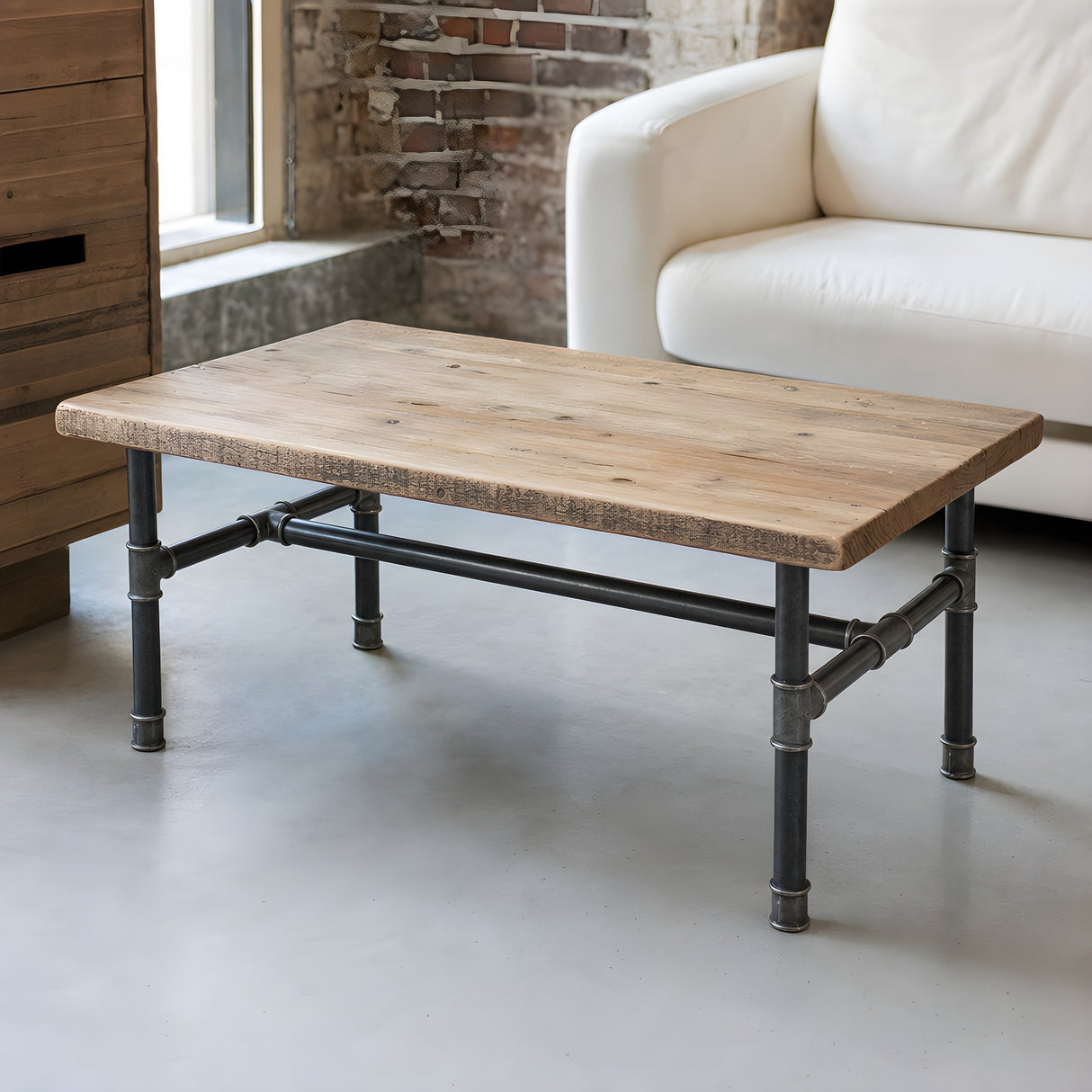 H-frame coffee table base, cast iron and varnished steel Ø 34 mm, shown in a room under a reclaimed pine tabletop